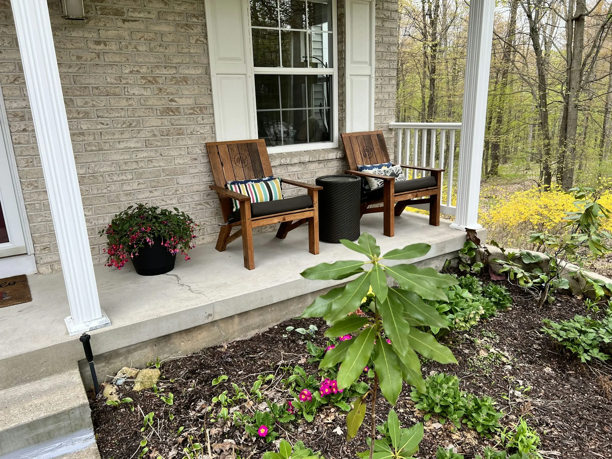 Front porch with two wooden chairs and fresh flower beds