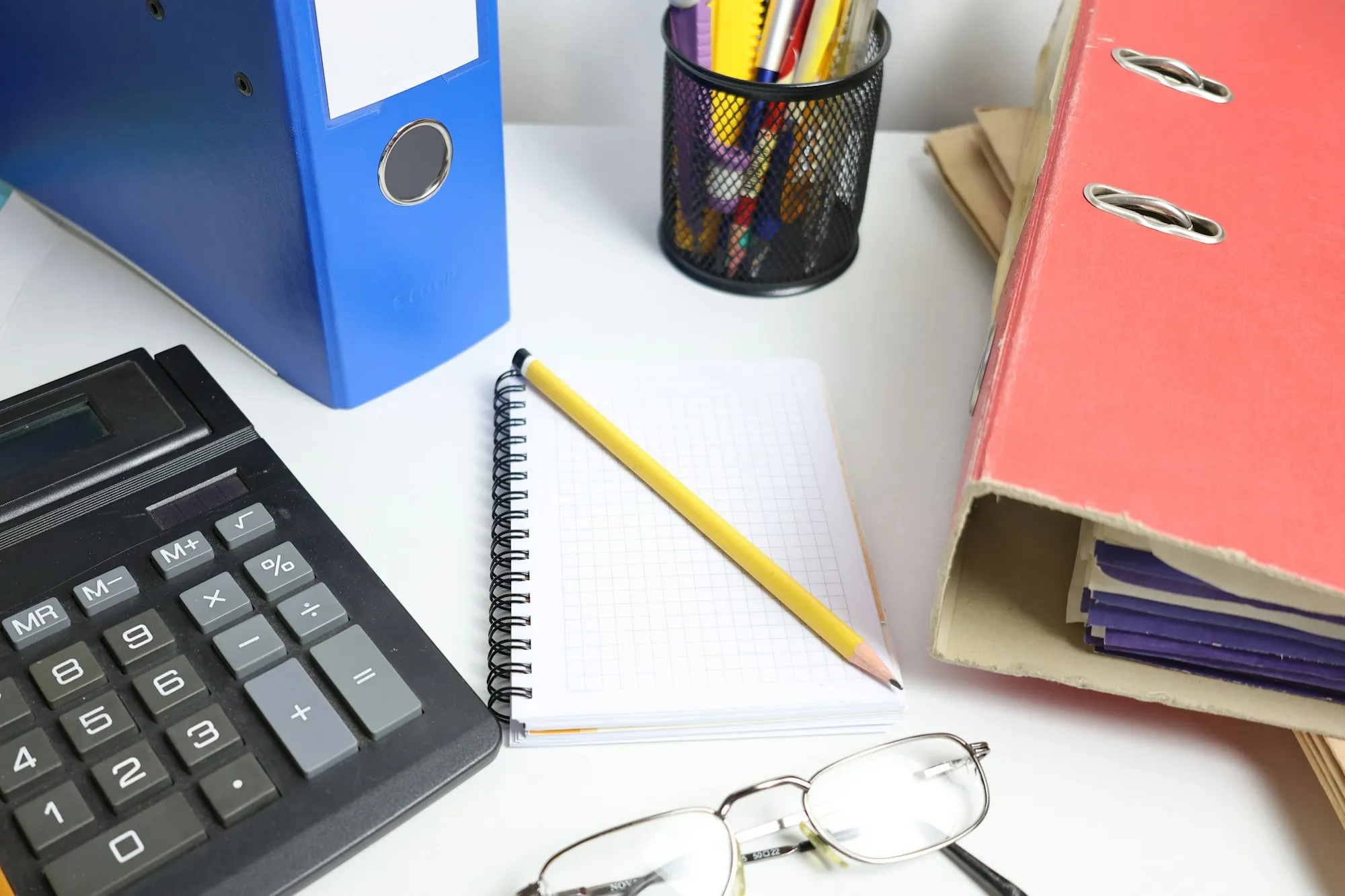 Desk with a calculator, notebook, folders and glasses