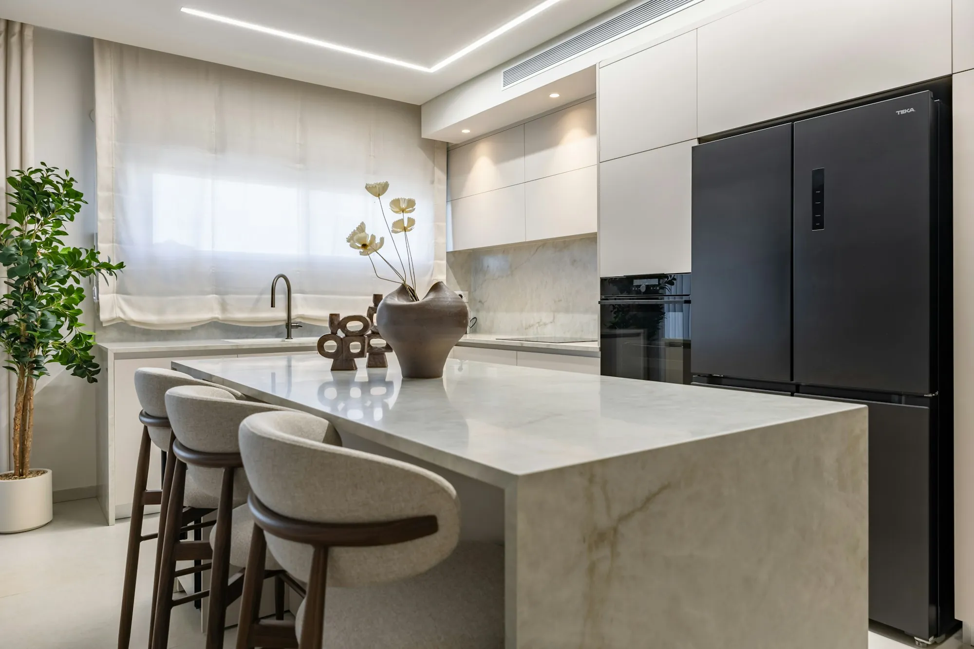 Marble kitchen island with curved bar stools and a black refrigerator